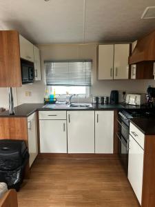a kitchen with white cabinets and a sink at Buttercup Retreat 298 northfield in Skipsea