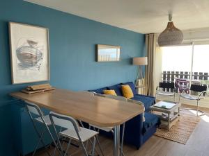 a living room with a table and a blue wall at Ocean View Oceanide in Lacanau-Océan
