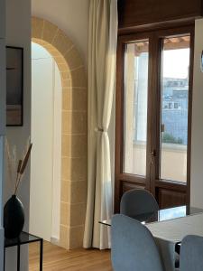 a dining room with a table and chairs and a window at EOS Suite Apartment - a due passi da Piazza Pisanelli e Ospedale Panico in Tricase