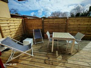 a patio with a table and chairs and a fence at Appartement à la Hume in Gujan-Mestras