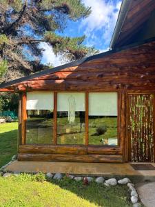 a wooden cabin with a window with a dog in a field at Cabañas monoambiente La Generosa LP in Lago Puelo