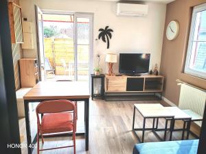 a living room with a television and a table and chairs at Appartement à la Hume in Gujan-Mestras