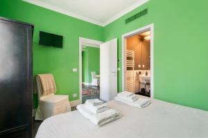 a green room with a bed with towels on it at Green House Historic Centre in Bologna