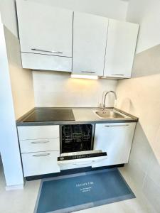 a white kitchen with a sink and a microwave at Mareline Seafront in Fano