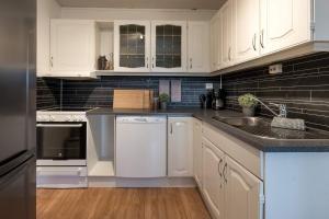 a kitchen with white cabinets and a sink at Modern Fjord View Apt near City in Tromsø