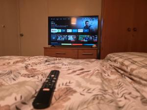 a remote control laying on a bed with a television at Private Home Grays in Orsett