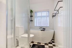 a white bathroom with a tub and a toilet at Swan House in Southport +15 photos