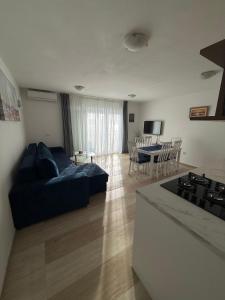 a living room with a blue couch and a kitchen at Apartment Perla in Dinjiška