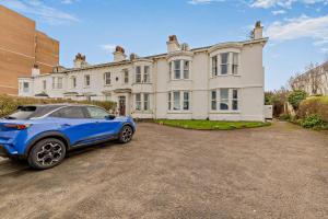 a blue car parked in front of a large house at Swan House in Southport