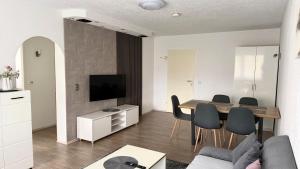 a living room with a table and chairs and a television at Ferienwohnung City in Nollingen