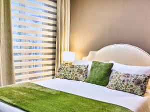 a bed with green and white pillows and a window at VILLA MARRONE - Relais - in Marsala +65 photos