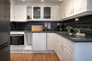 a kitchen with white cabinets and a sink at Modern Fjord View Apt near City in Tromsø +8 photos
