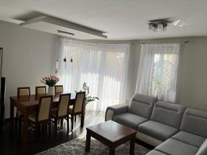 a living room with a couch and a table and chairs at Ogrodowa Apartament in Ciechocinek +4 photos