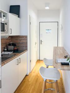 a kitchen with white cabinets and a counter with two stools at My Room Messe Munich Apartment in Munich