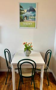 a white table with two chairs and a vase with flowers on it at Vichy Cosy T2 plein centre, thermes et parcs in Vichy