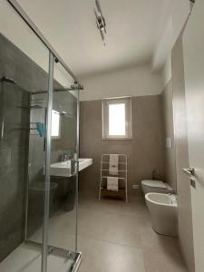 a bathroom with a shower and a toilet and a sink at Fortezza Apartments in Le Castella