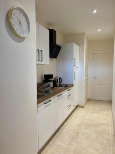 a kitchen with white cabinets and a clock on the wall at Vichy Cosy T2 plein centre, thermes et parcs in Vichy