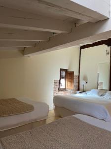 a bedroom with two beds and a mirror on the wall at Hotel Rural El Zaguán in Lerma