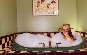 a woman in a bath tub with a cowboy hat at Bisbee Grand Hotel, Saloon, and Music Venue in Bisbee