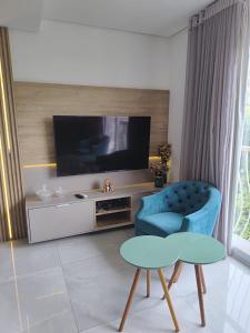 a living room with a tv and a blue chair at Edifício Capri , apto 405 Canela RS in Canela