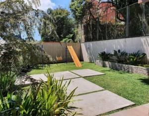 a garden with a wooden board in the grass at Edifício Capri , apto 405 Canela RS in Canela