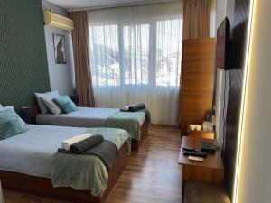 a hotel room with two beds and a television at Zulu Apartments and Studios in Kumanovo