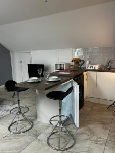 a kitchen with a table and two bar stools at Lilyscape At Whitehead in Whitehead +4 photos