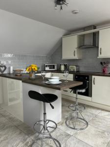 a kitchen with a counter and two bar stools at Lilyscape At Whitehead in Whitehead