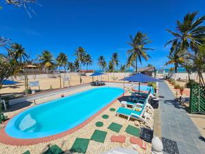 a pool with chairs and umbrellas next to the beach at Hotel Pousada Cachalote in Coruripe