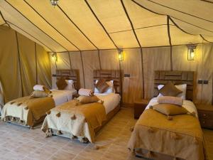 a bedroom with two beds in a tent at Achabou Desert Camp in Merzouga