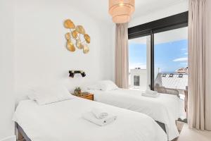 two beds in a room with a window at Luxury Apartment Higueron in Fuengirola +13 photos