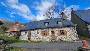 an old stone house with a blue roof at Belle résidence auvergnate Vue panoramique sur la nature in Saint-Julien-de-Jordanne