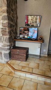 a room with a counter with a tv and a stone wall at Belle résidence auvergnate Vue panoramique sur la nature in Saint-Julien-de-Jordanne