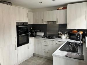 a kitchen with white cabinets and a stove top oven at Waverley 3-Bed Springfields House in Rotherham