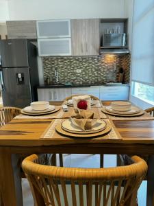 a wooden table with plates and an apple on it in a kitchen at 31 Exclusive Cabin with Private Jacuzzi, Beach in Tubará