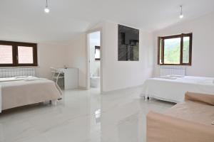 a white room with two beds and a mirror at FarmVille B&B in Moliterno