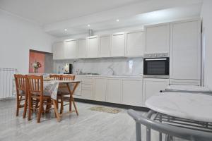 a kitchen with white cabinets and a table and chairs at FarmVille B&B in Moliterno