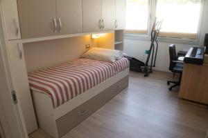 a small bed in a room with a desk at Cernobbio Apartment in Cernobbio