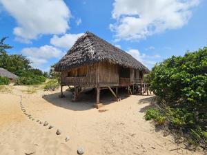 a hut with a straw roof on a beach at Bone Idle, Lamu Beach Home in Lamu