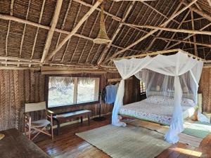 a bedroom with a canopy bed and a chair at Bone Idle, Lamu Beach Home in Lamu