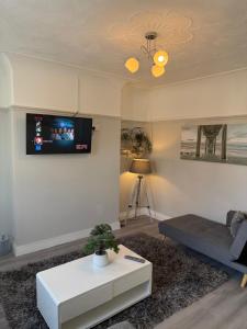 a living room with a couch and a tv on the wall at Cosy 2 Bed By Pleasure Beach in Blackpool