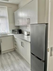 a kitchen with white cabinets and a stainless steel refrigerator at Cosy 2 Bed By Pleasure Beach in Blackpool