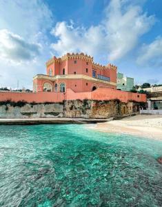 a building on the beach with the water in front at EOS Suite Apartment - a due passi da Piazza Pisanelli e Ospedale Panico in Tricase