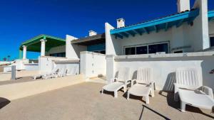 a group of white chairs sitting outside of a building at Charming and Cozy Beachfront Condo - Las Olas II 3 in Puerto Peñasco