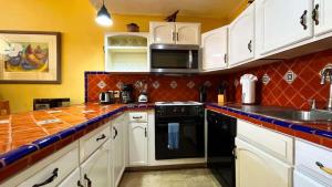 a kitchen with white cabinets and a black dishwasher at Cozy Ground Level Condo near Pool Pinacate 112 in Puerto Peñasco
