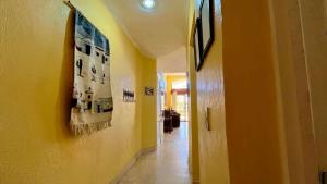 a hallway with a yellow wall with pictures on the wall at Cozy Ground Level Condo near Pool Pinacate 112 in Puerto Peñasco
