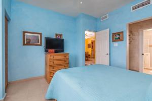 a blue bedroom with a bed and a television at Serene & Warm 3rd Level Condo - Corona del Mar 302 in Puerto Peñasco