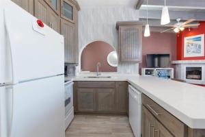 a kitchen with a white refrigerator and wooden cabinets at Cozy & Beautiful Beachfront Condo Las Olas II 2 in Puerto Peñasco