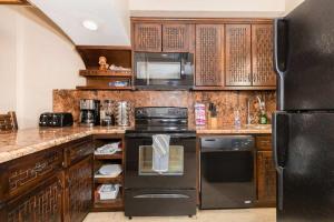 a kitchen with wooden cabinets and a black refrigerator at Unique Oceanfront with Epic Sunsets Pinacate 202 in Puerto Peñasco