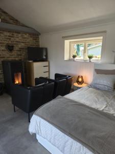 a bedroom with a bed and chairs and a fireplace at Haillodge-gîte nature in Ohey